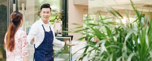 Small business owner greeting a pedestrian passing his store.