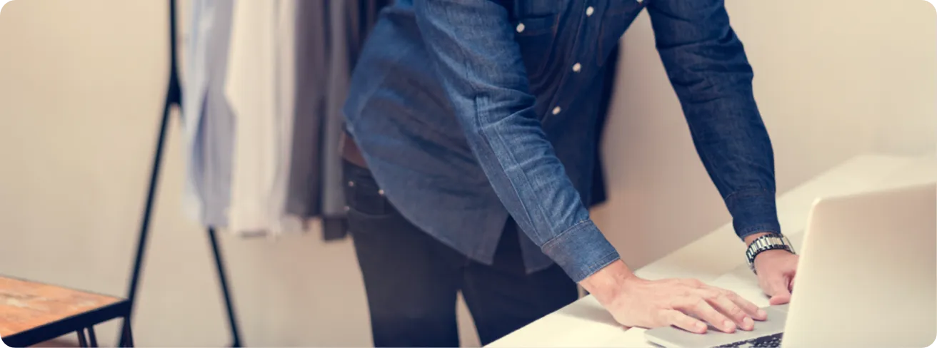 Person standing behind a counter, working on a laptop.
