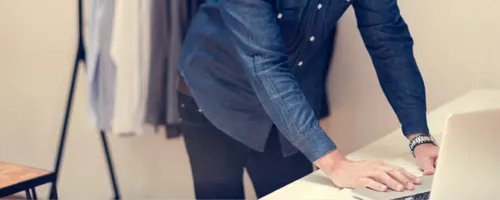 Person standing behind a counter, working on a laptop.