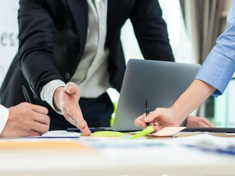 A corporate meeting in progress with a laptop computer on the table.