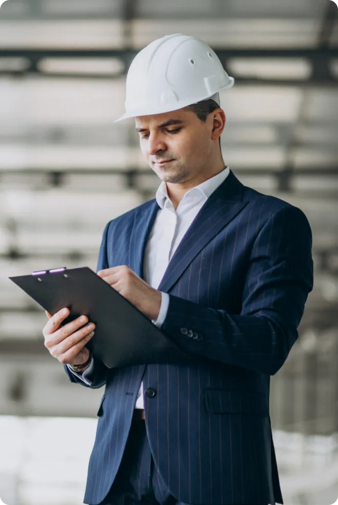 Businessman wearing a hard hat with a clipboard.