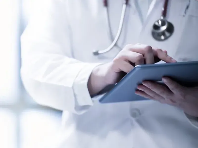 A doctor wearing a stethoscope, working on a tablet.