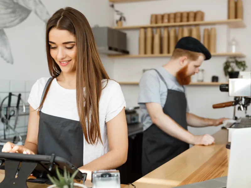 Two baristas working behind the counter of a coffee shop.