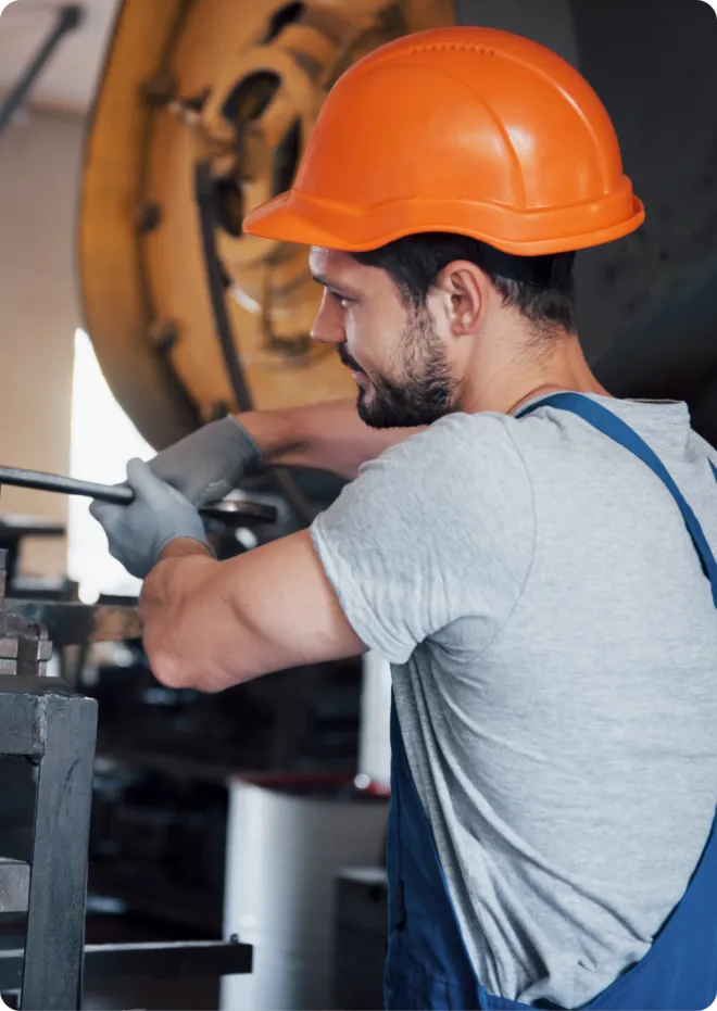 Man in an orange helmet working in a factory.