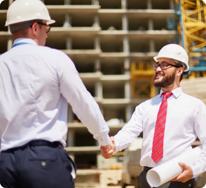 Two men in white hardhats shaking hands.