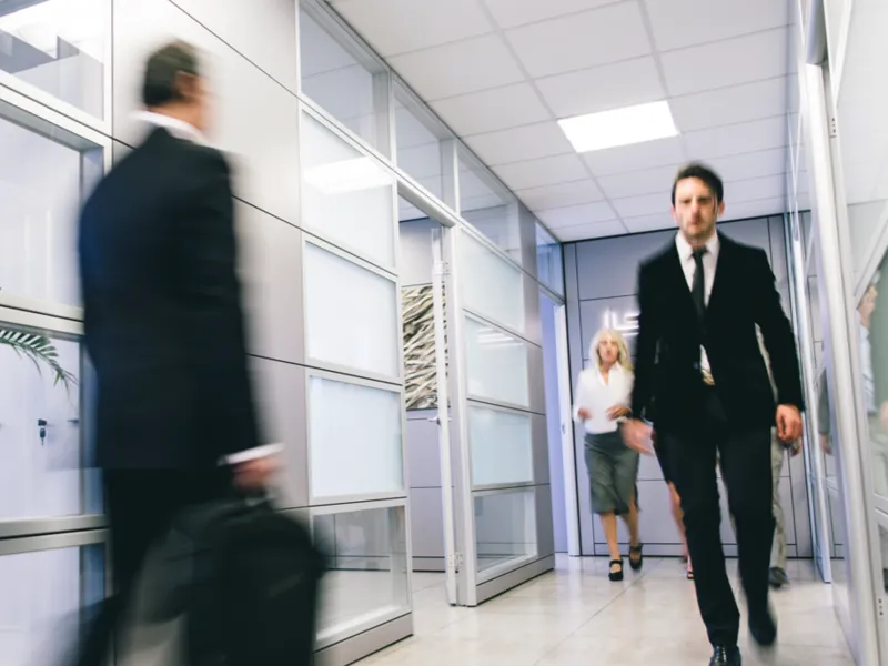 A man in a suit rushes down a hallway