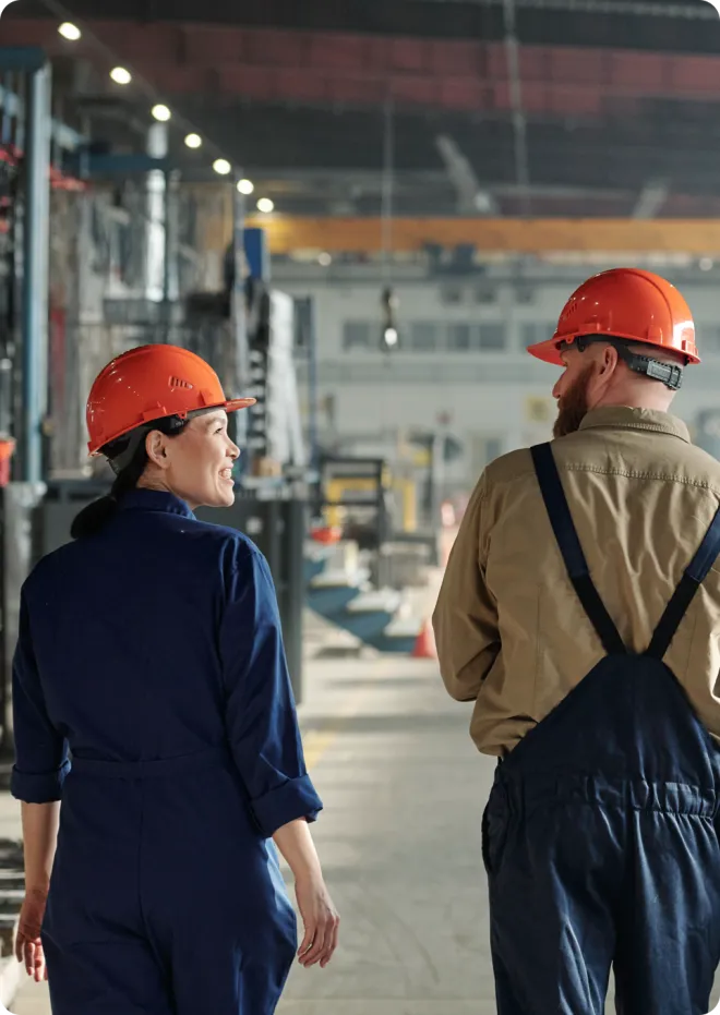 Man and woman in a warehouse wearing blue PPE.