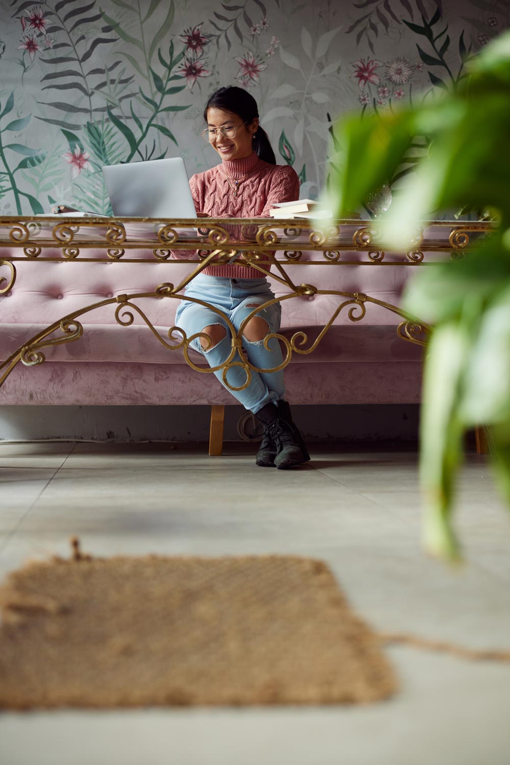 A young woman smiles as she works on her laptop