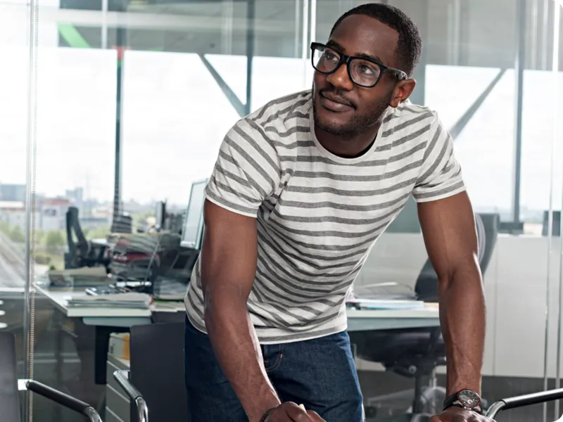 A person wearing a black framed glasses, in a office setting.