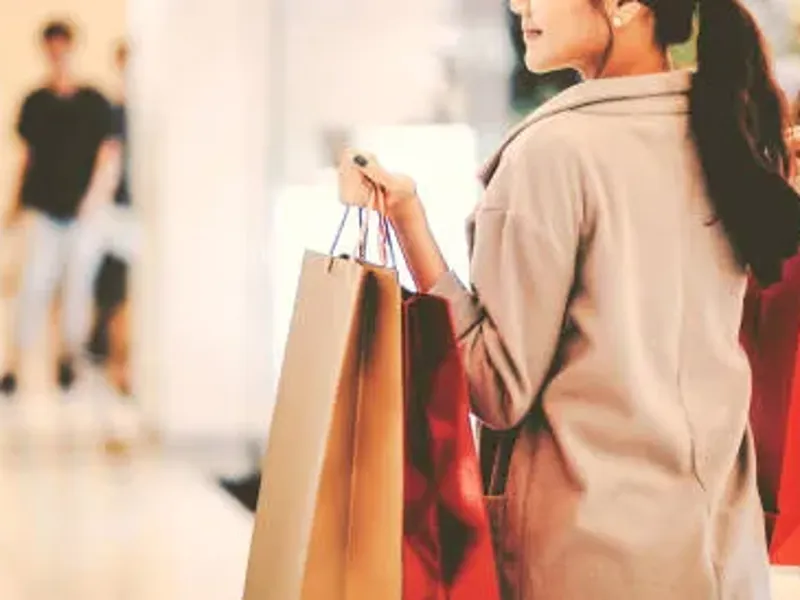 Shopper in a shopping mall, walking past stores.