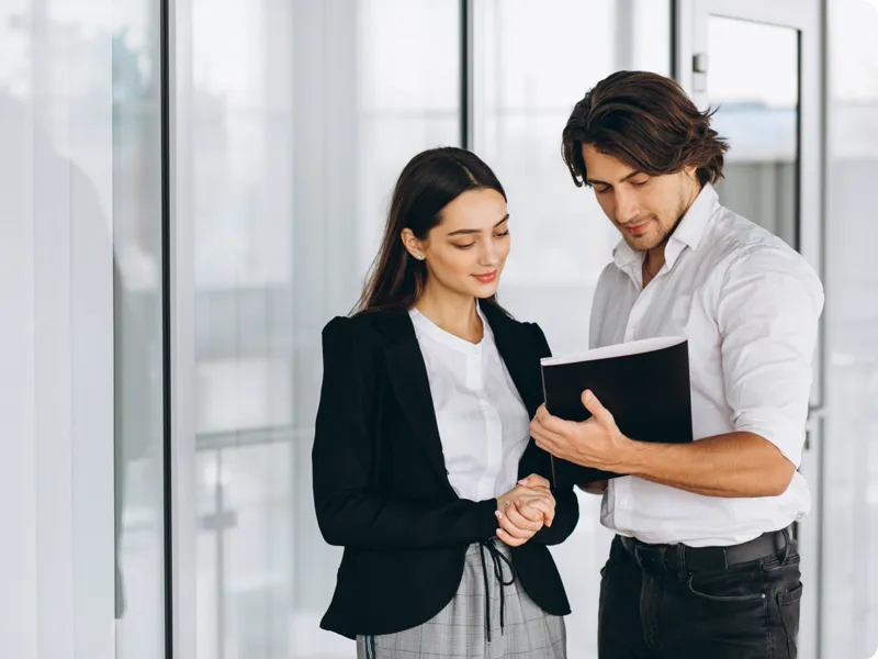 Two people stand as they study a document