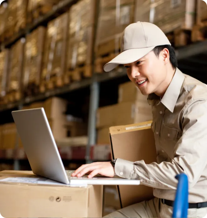Man in a warehouse using a laptop.