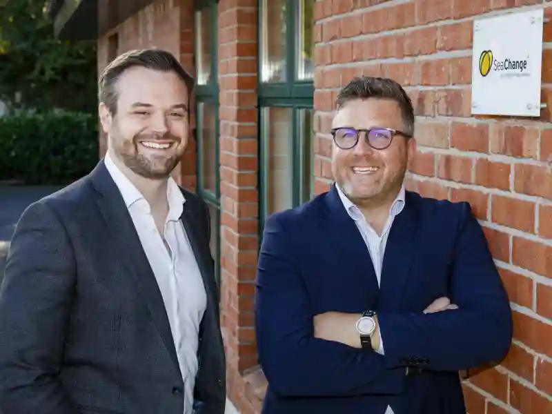 Two SeaChange employees posing next to a brick wall.